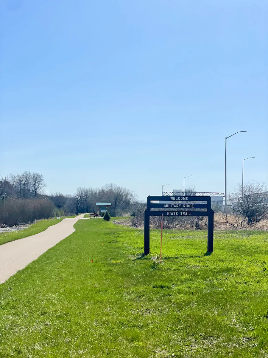 Bike path with sign naming the path - Military Ridge State Trail - and grass on one side. 