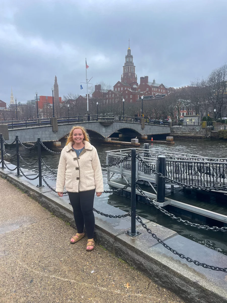 Woman standing in front of the Providence River with College Hill in the background. 