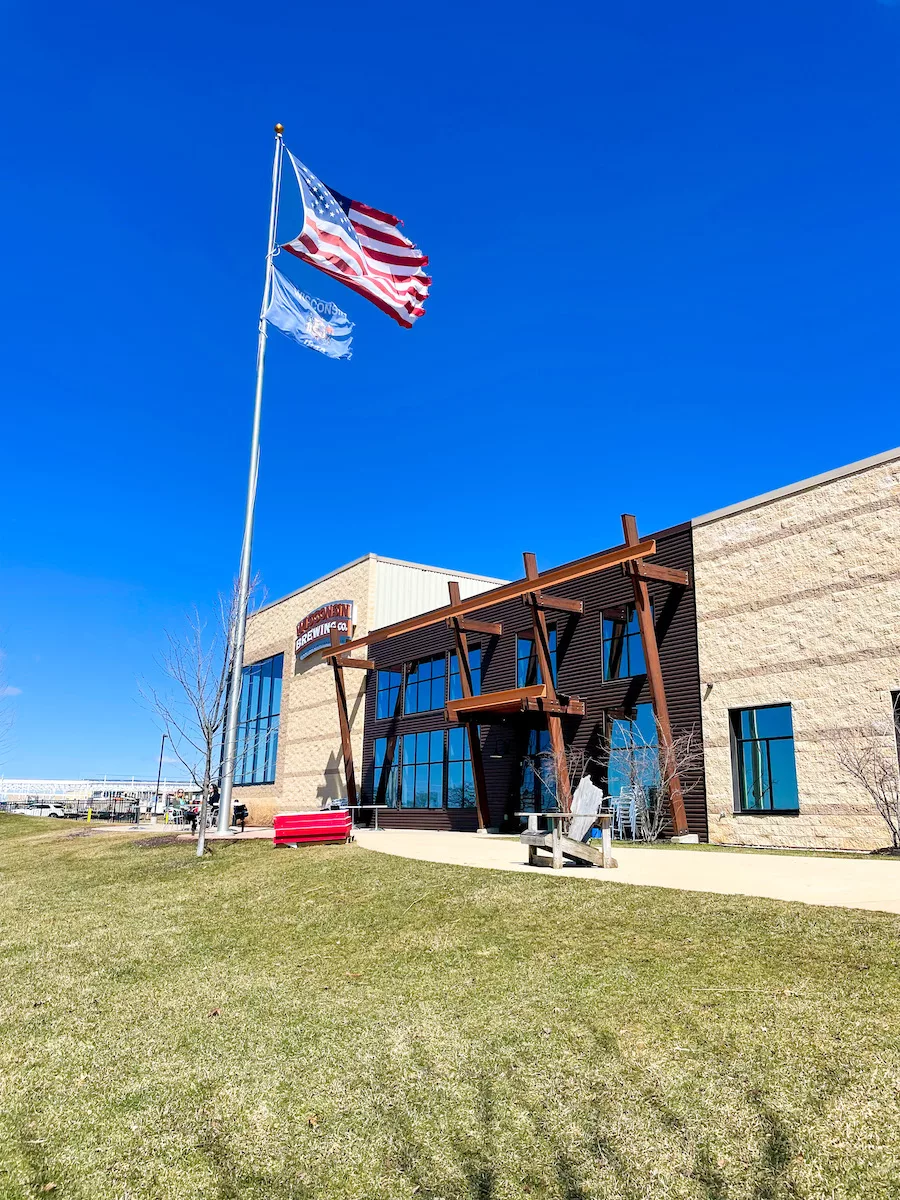 Brewery in Madison, WI surrounded grass and a couple flags. 