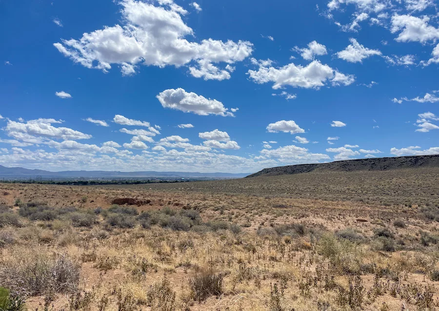 View from a canyon in Petroglyph National Monument of blue, cloudy sky and mountains in the distance. 