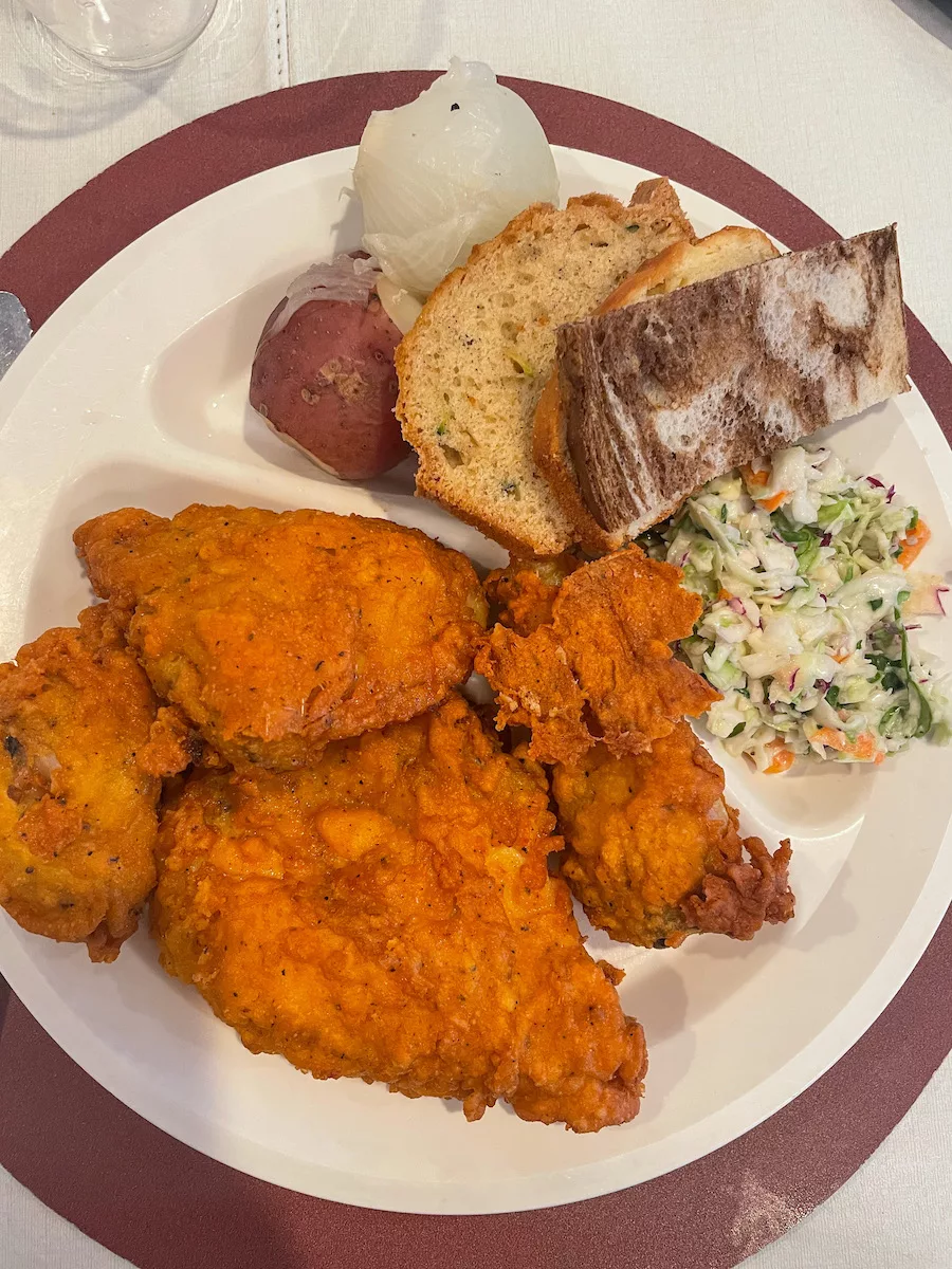 Dinner Plate full of chicken, potatoes, bread and coleslaw. 