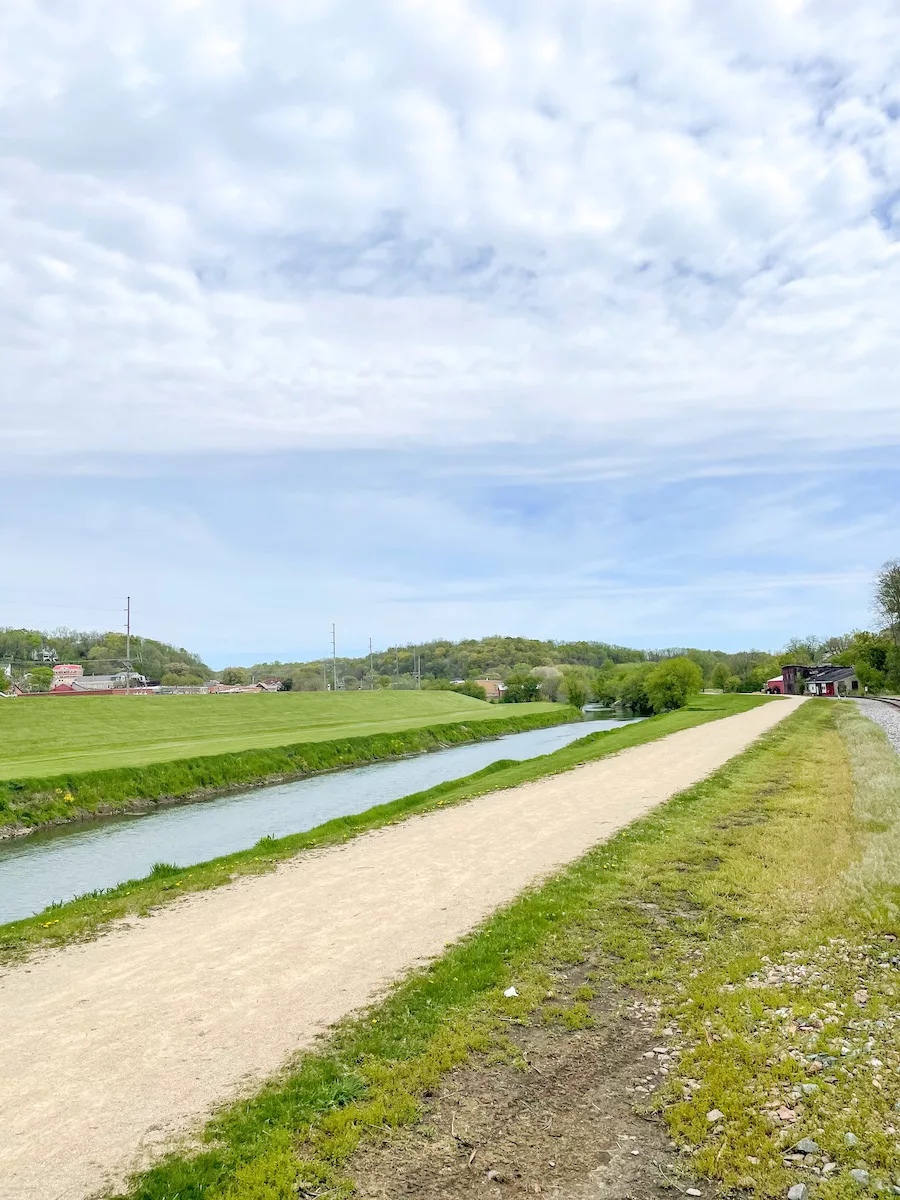 View of the Galena River Trail and the Galena River. Cloudy blue sky above. 