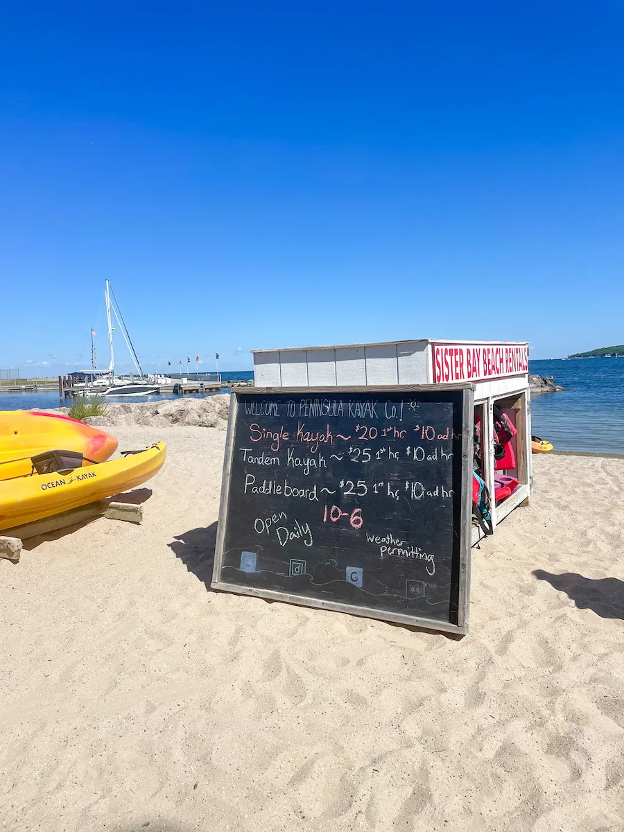 Sandy beach with kayaks and rental sign in Door County, Wisconsin