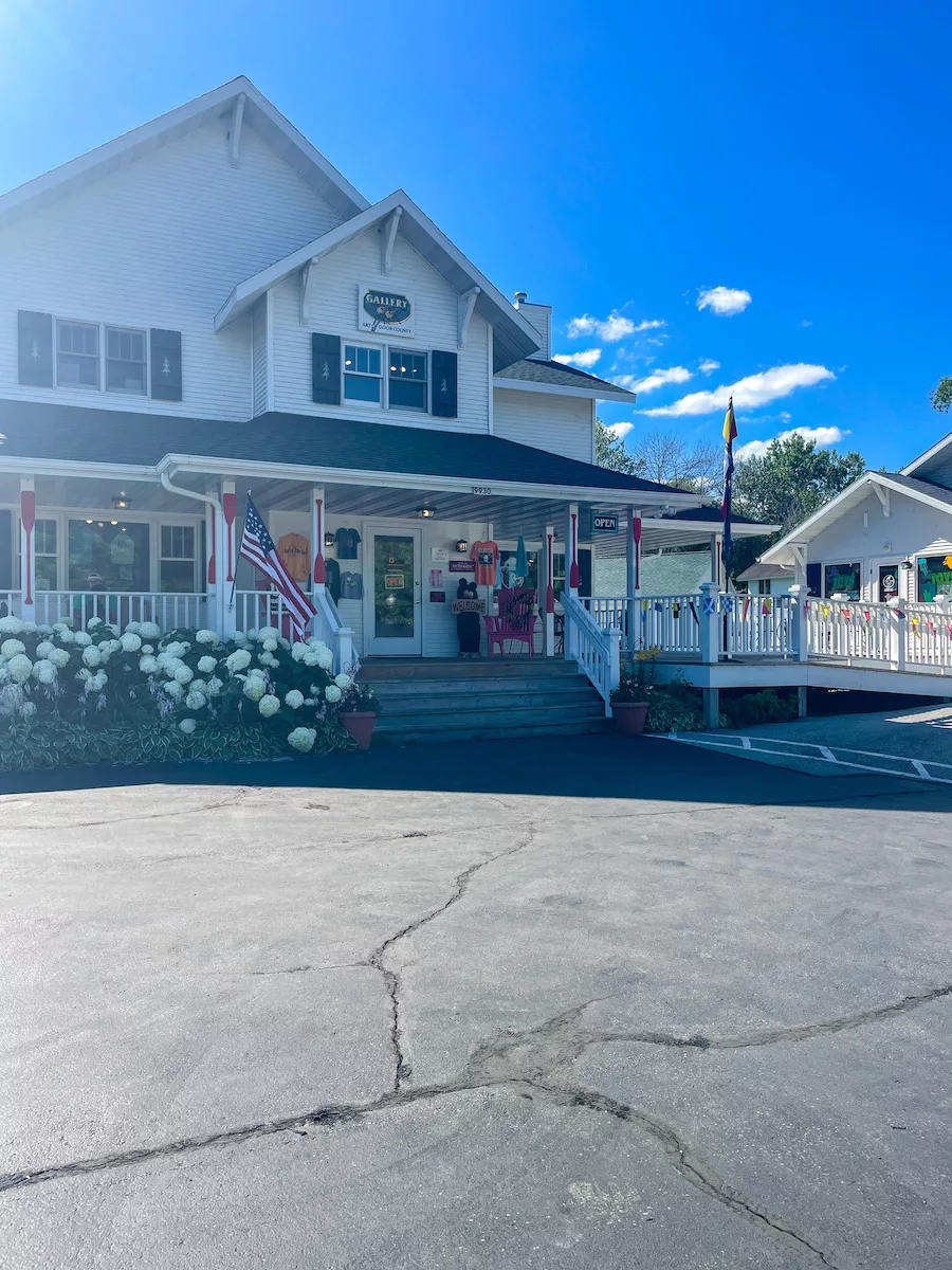 Shopping center surrounded by cloudy blue skies and flowers.