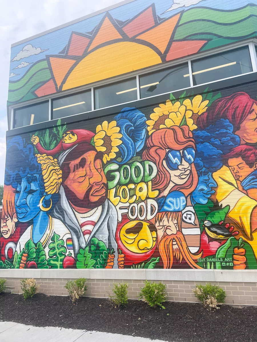 Colorful mural on the side of a building in KCK of people, food and sunflowers. 