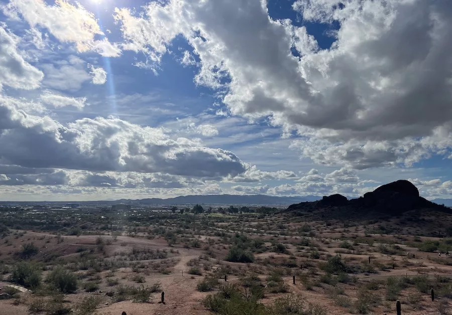 View from above of desert mountains in Arizona with a cloudy sky and a sunbeam peeping through 