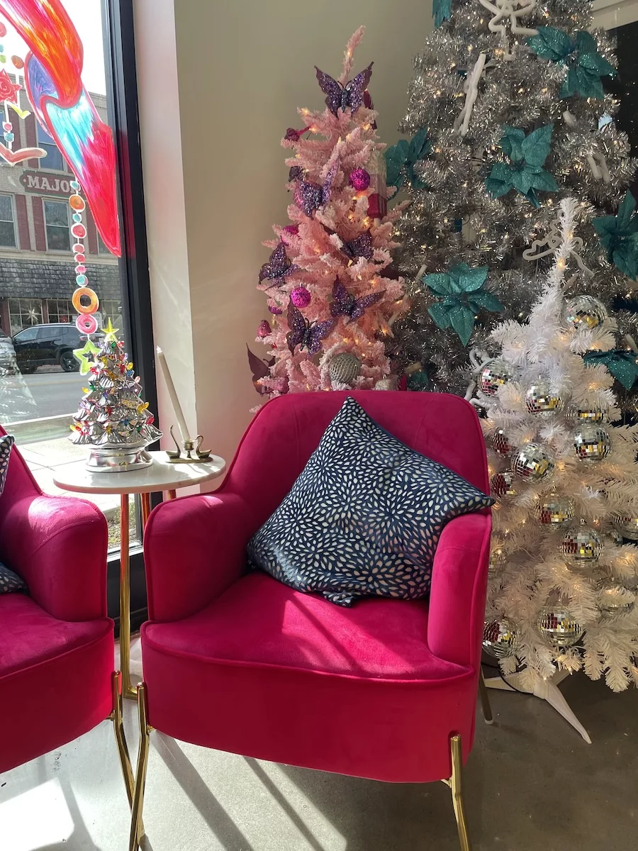 Pink chair with three decorated Christmas Trees behind it (pink, white and silver) at Tiphanies in Downtown Davenport
