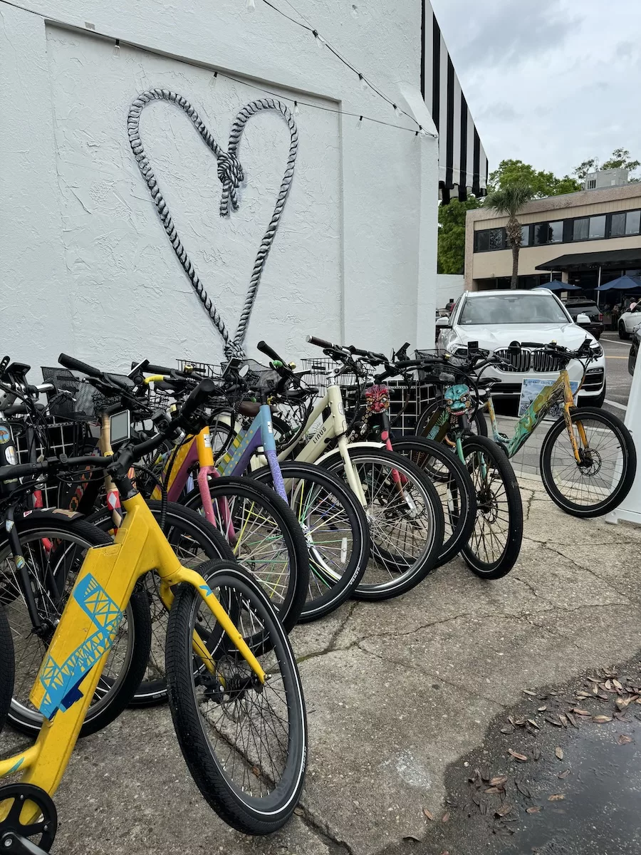 Painted e bikes in front of heart mural at Art Bikes in Jacksonville, FL