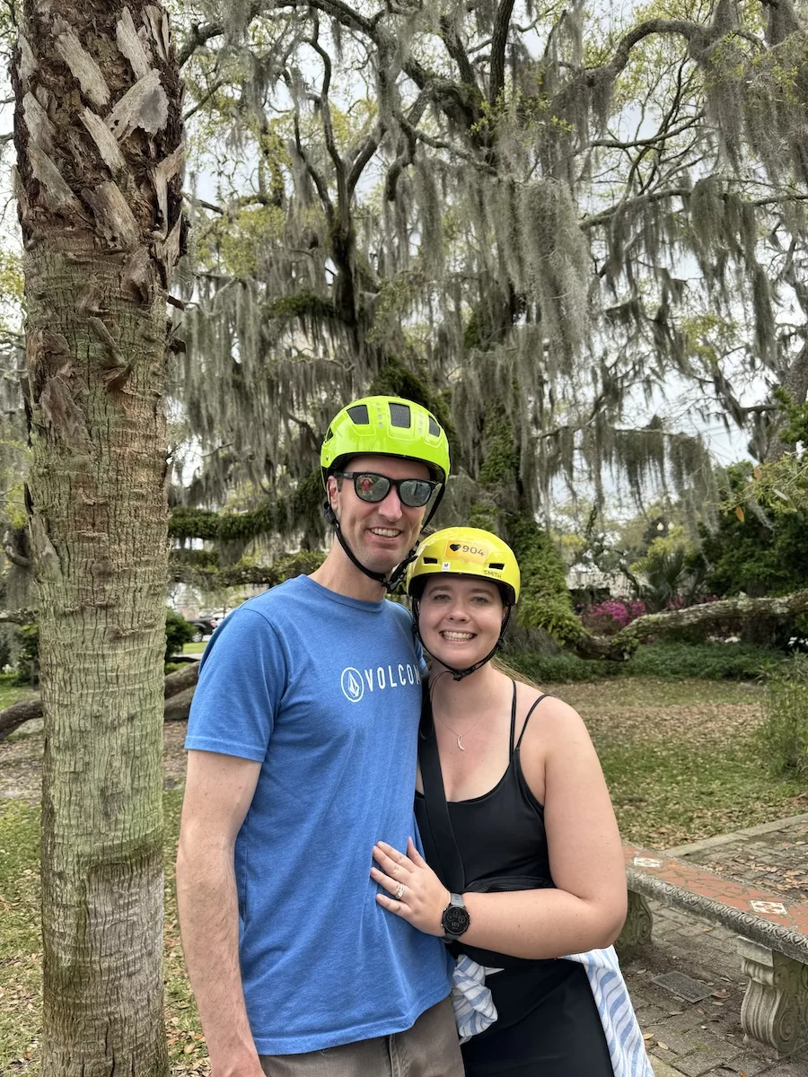 Man and woman wearing neon-colored bike helmets in front of oak tree in Jacksonville, FL 
