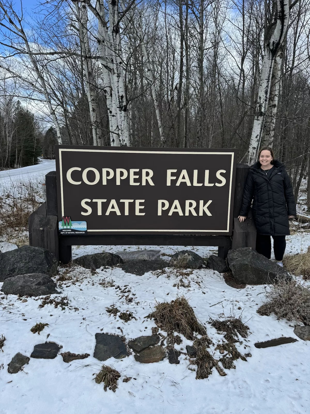 Guide to Copper Falls State Park - Image of woman posing next to state park entrance sign
